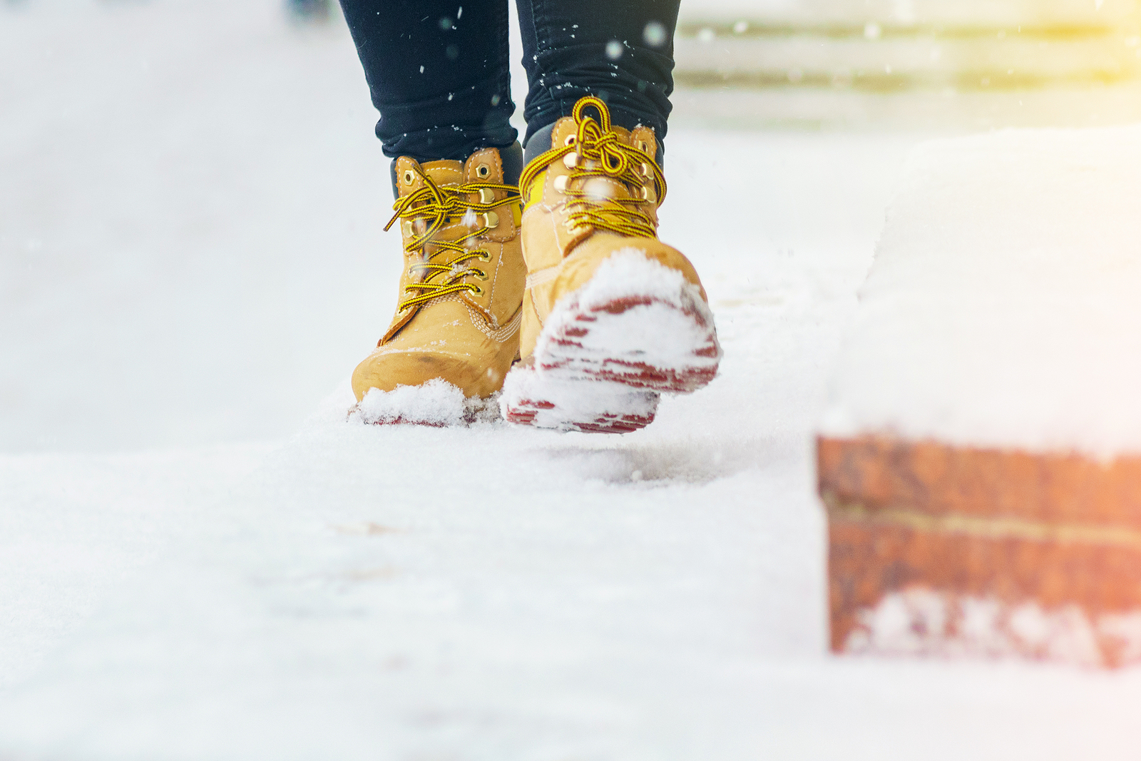 A Woman In Yellow Leather Shoes Is Walking Along A Snowy Pavemen
