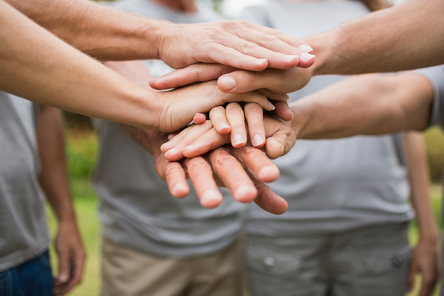 Happy volunteer family putting their hands together on a sunny d
