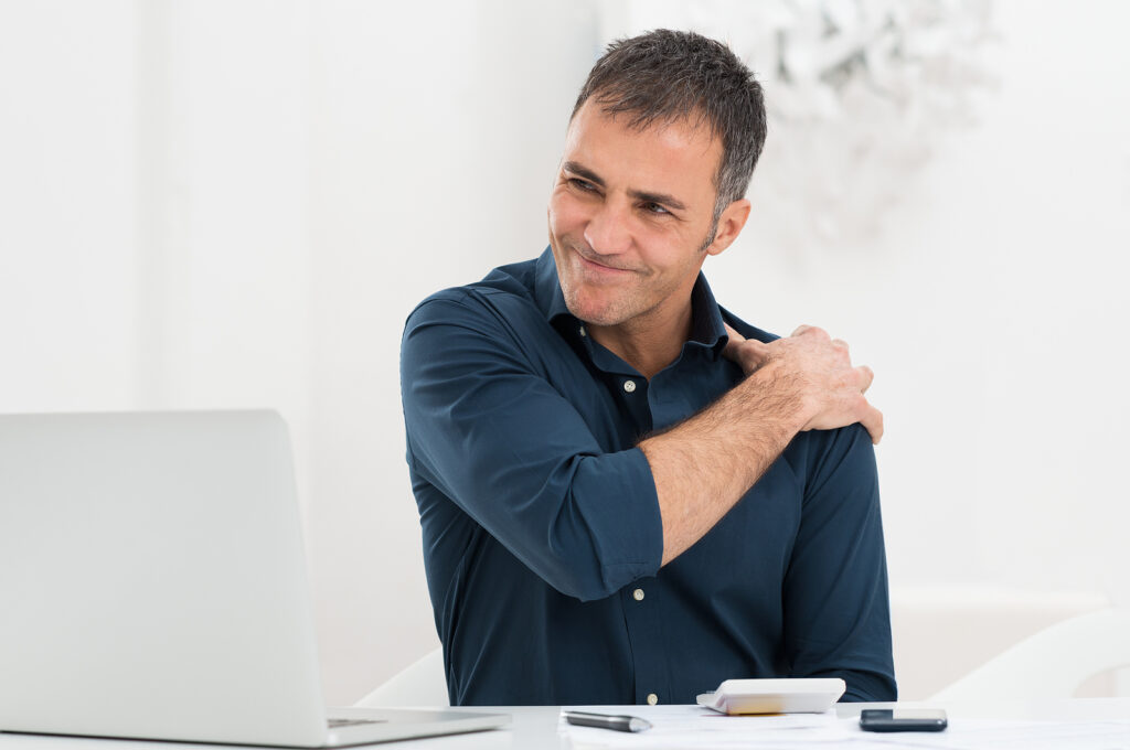 Portrait Of Mature Man At Work Suffering From Shoulder Pain